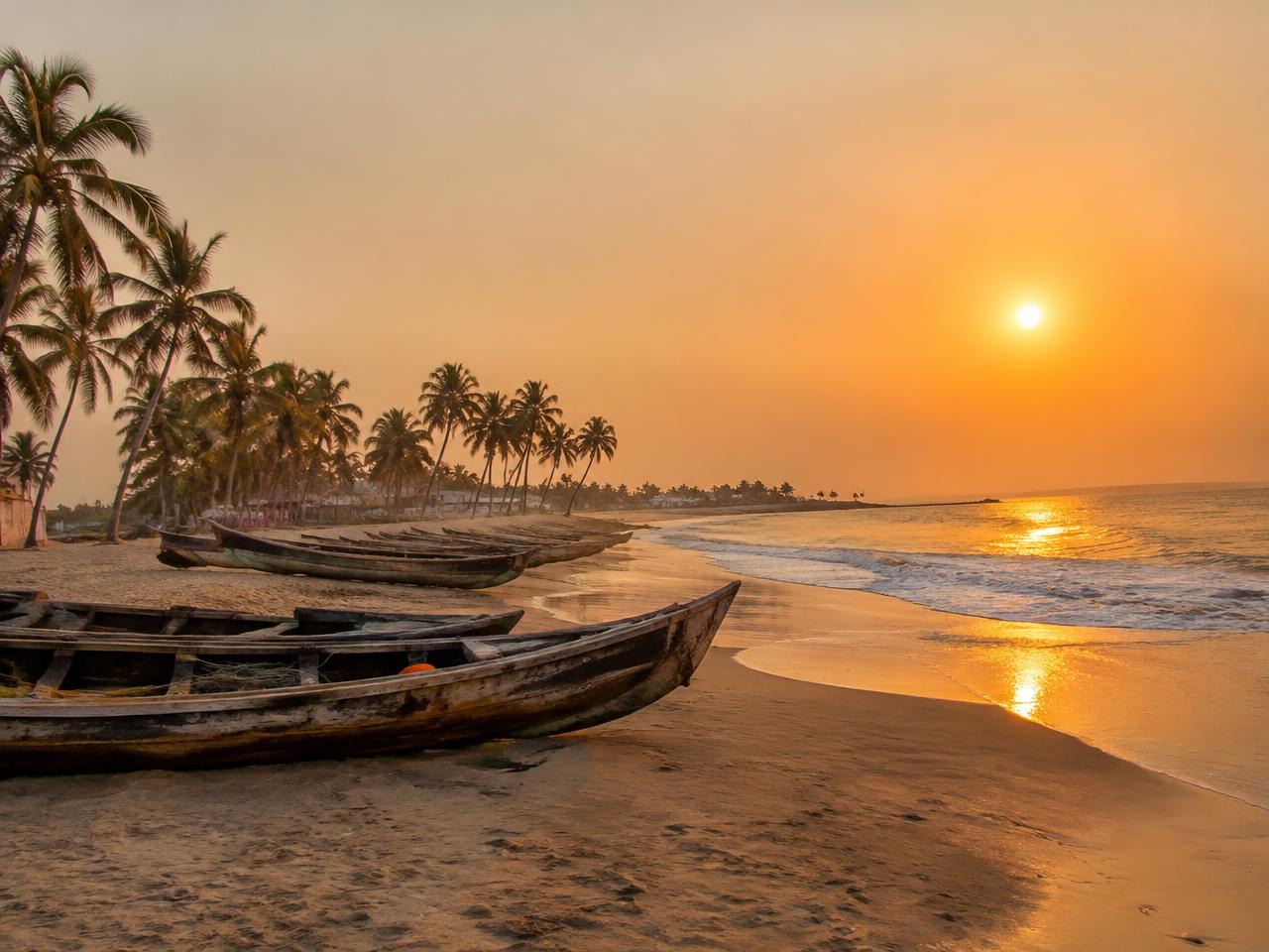 Ghana beach at sunset with fishing canoes (illustrative image)